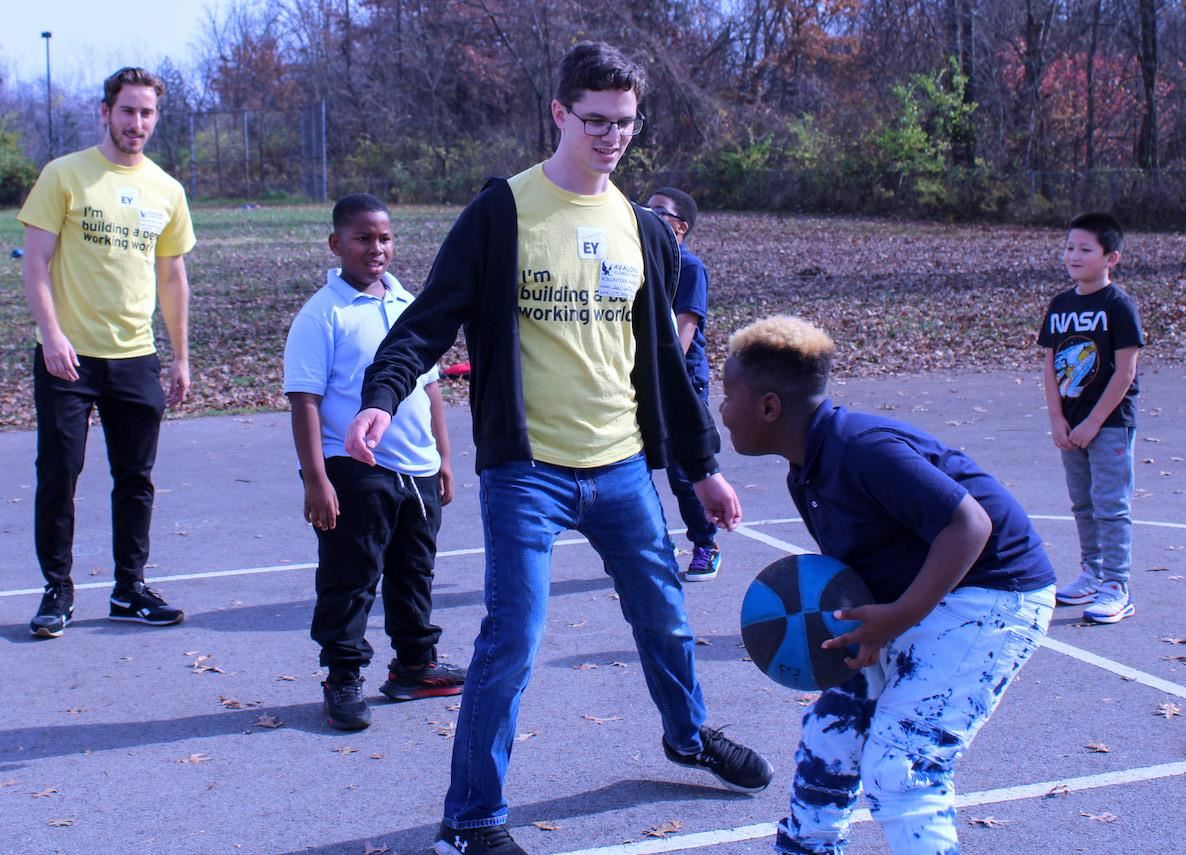 Ernst and Young staff playing basketball with students